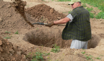 Rugged man digging deep hole with shovel